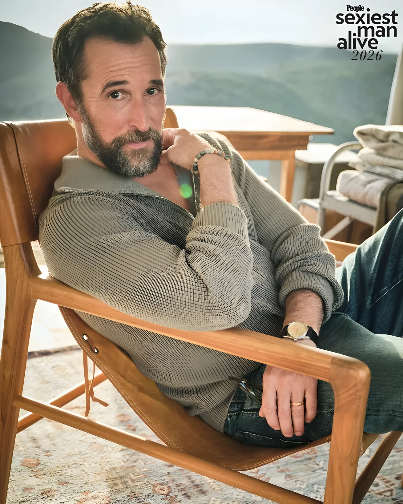 Noah Wyle seated in a wooden chair in a relaxed pose