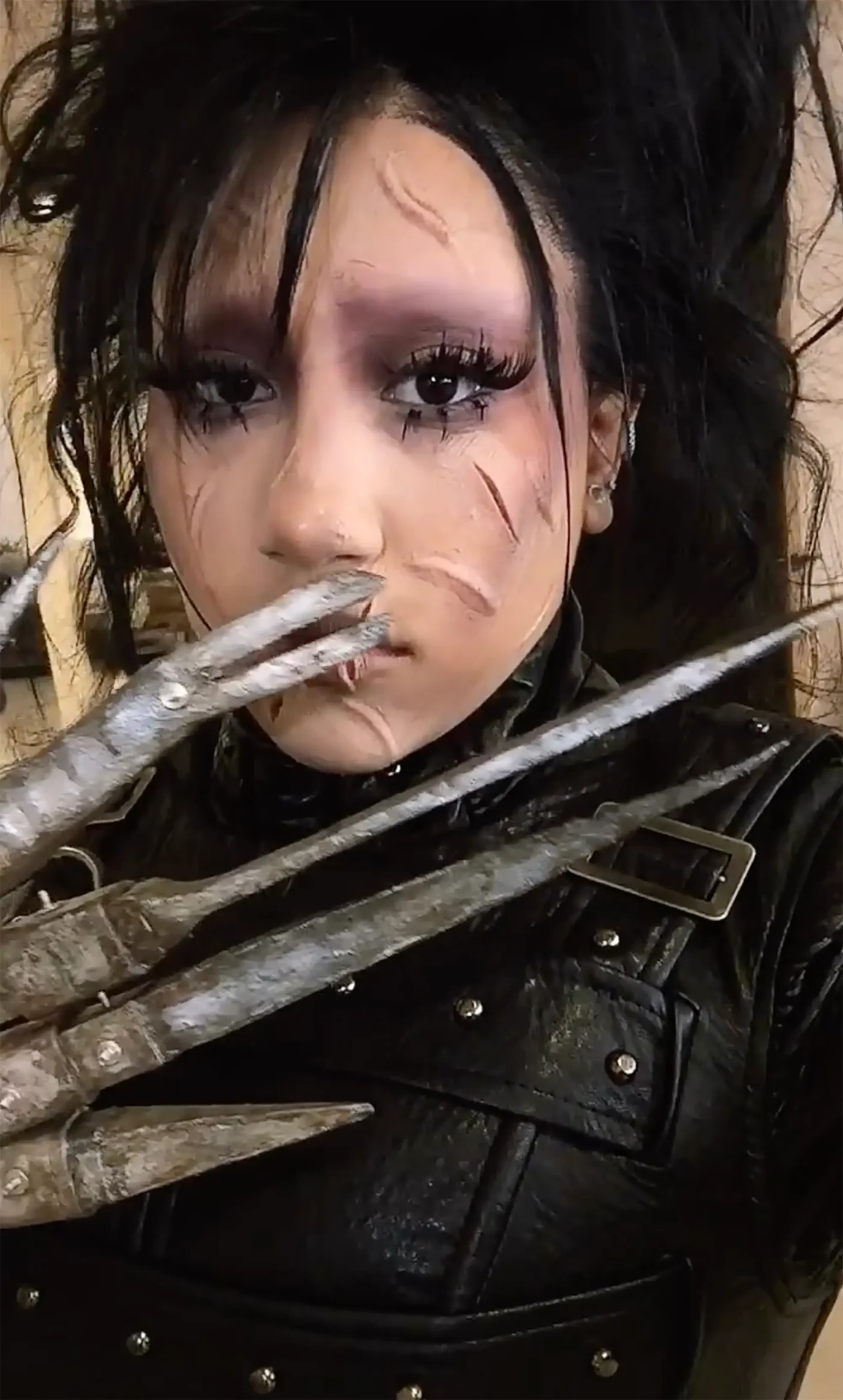 North West dressed as Edward Scissorhands with scarred makeup, wild hair, and metal scissor fingers.