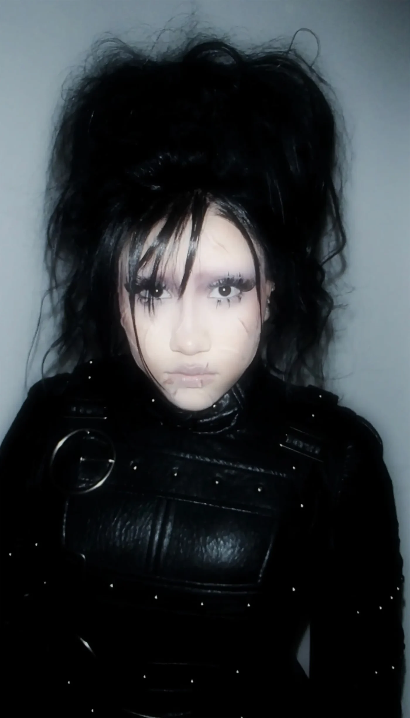 North West in an Edward Scissorhands costume with pale makeup, scars, wild black hair, and a black leather outfit.