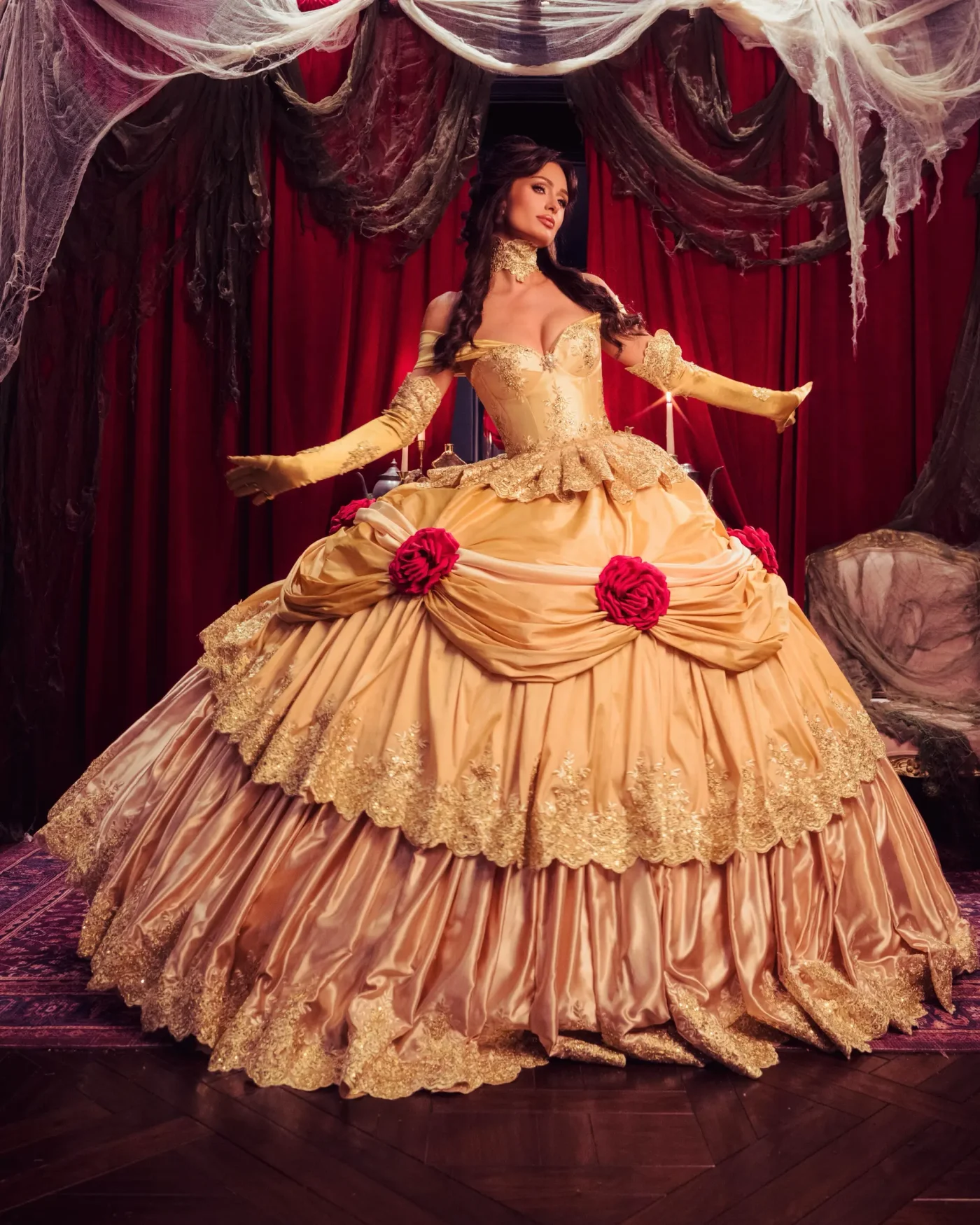 Paris Hilton poses in a Beauty and the Beast costume, featuring a large, tiered golden gown adorned with red roses.