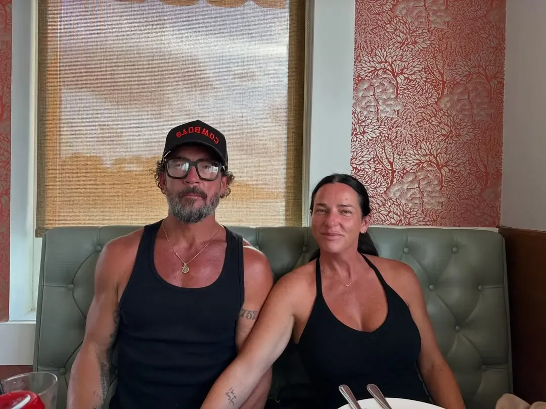 Pastor Carl Lentz and his wife Laura Lentz sitting together in a booth.