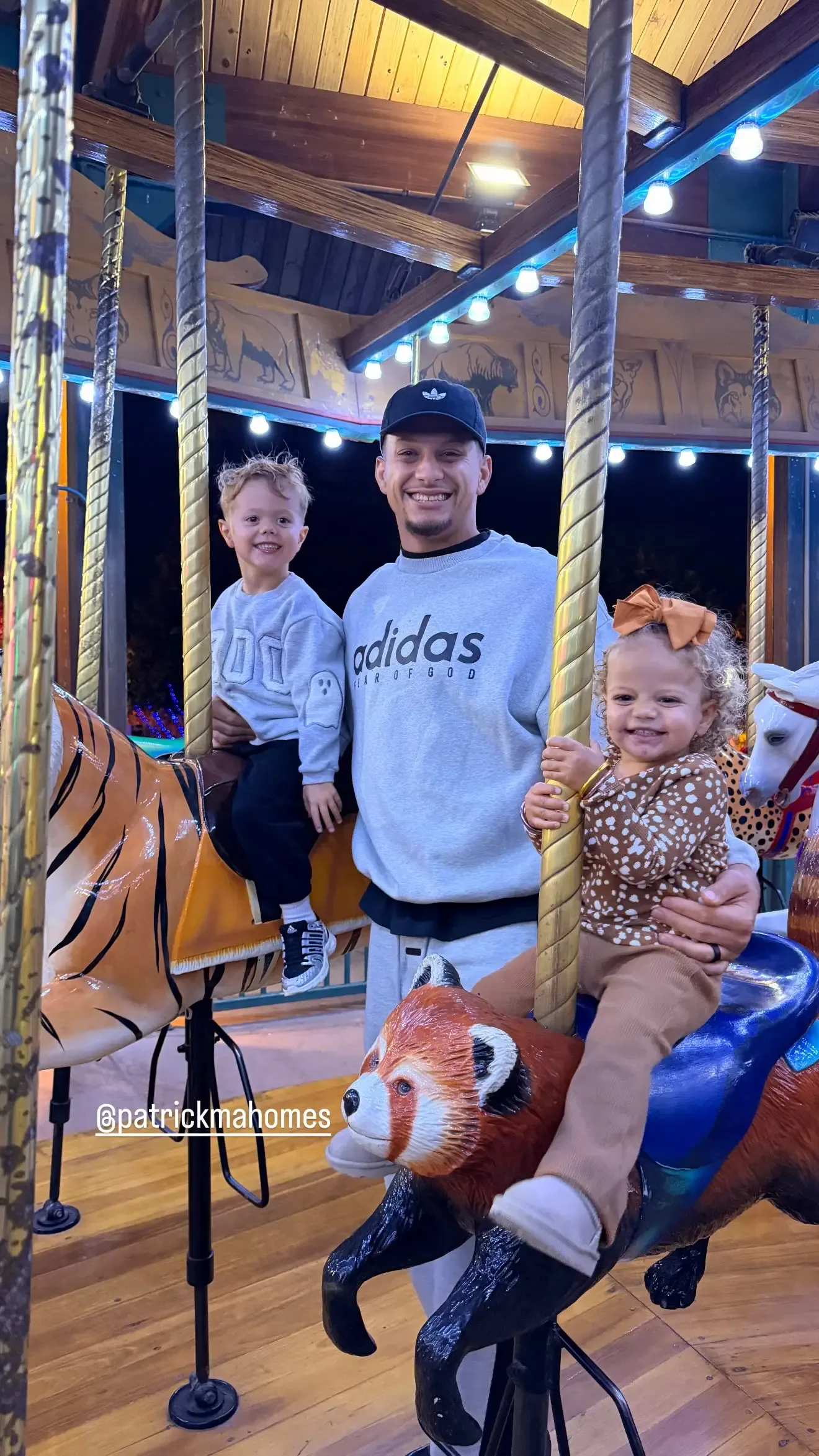 Patrick Mahomes smiles on a carousel with his son sitting on a tiger and his daughter riding a red panda.