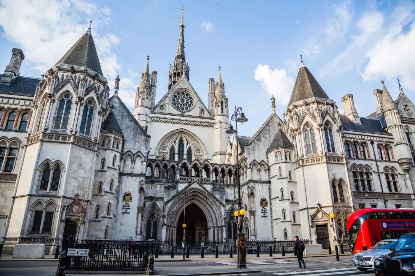 People crossing the road in front of the Royal Courts of Justice in London.