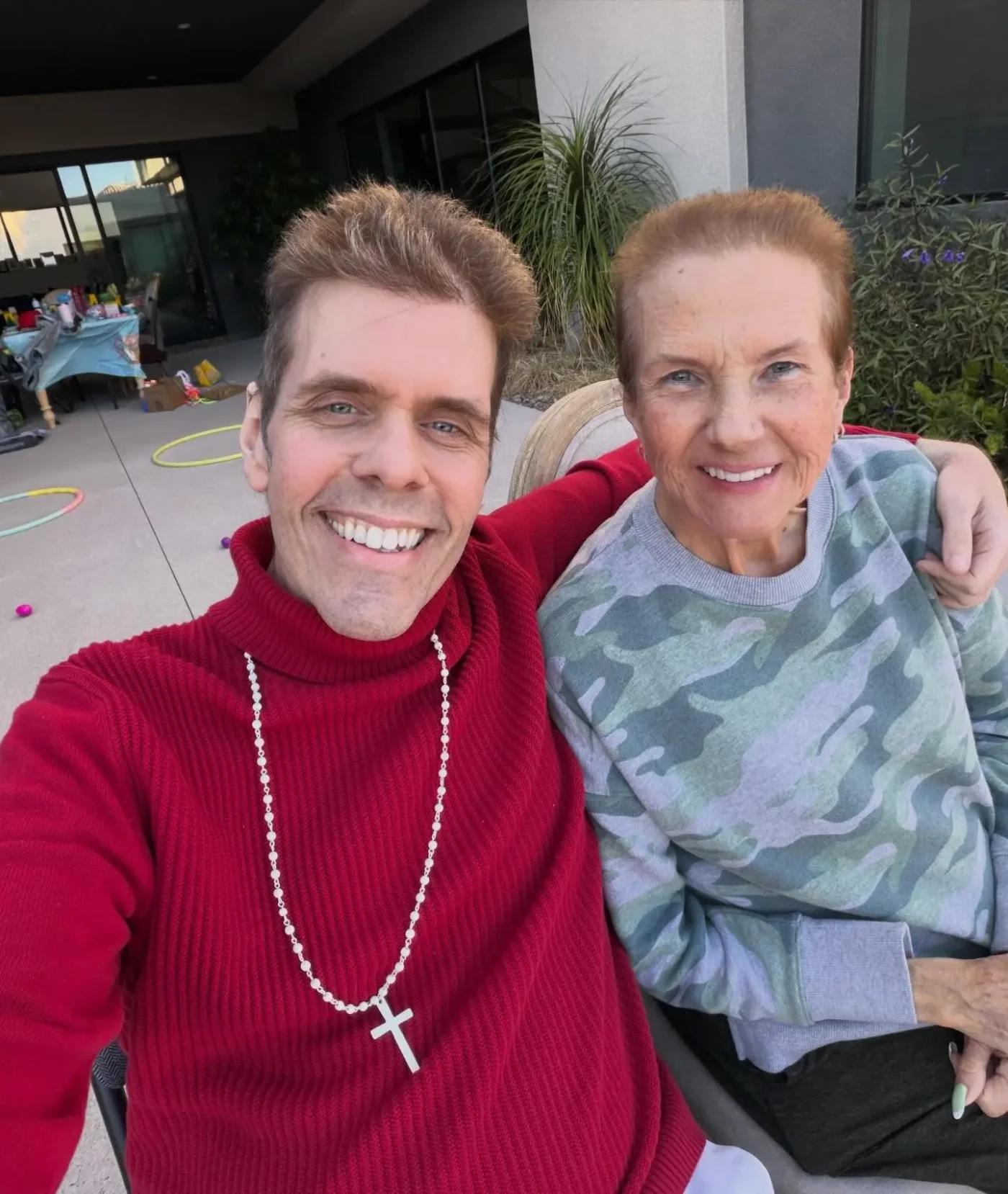 Perez Hilton and his mom sitting together outdoors.
