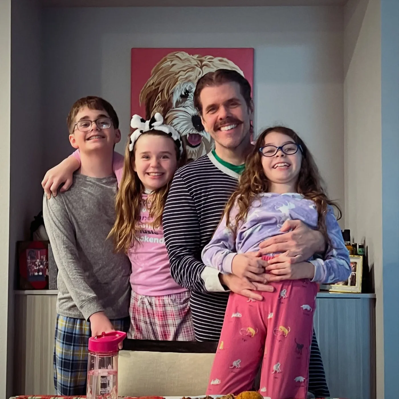 Perez Hilton and his three children smiling together in matching pajamas.