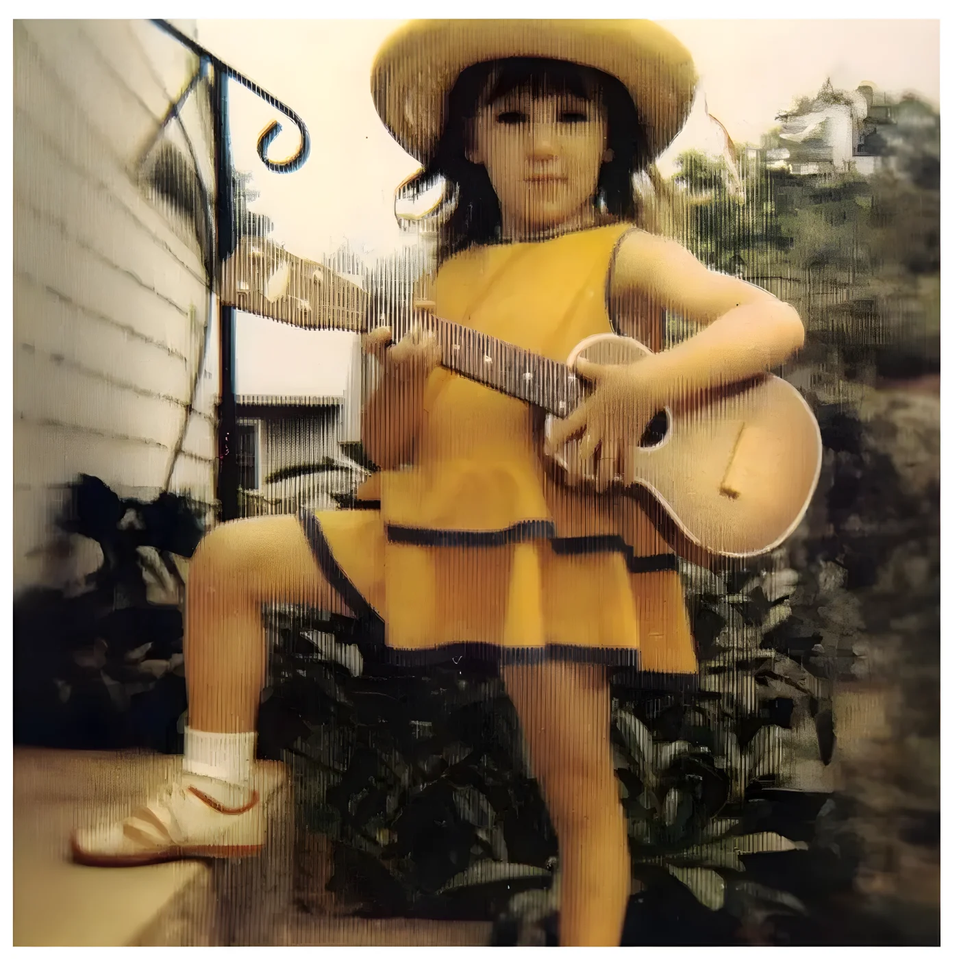 Picture of a young Debbie Gibson in a yellow dress and sunhat holding a guitar