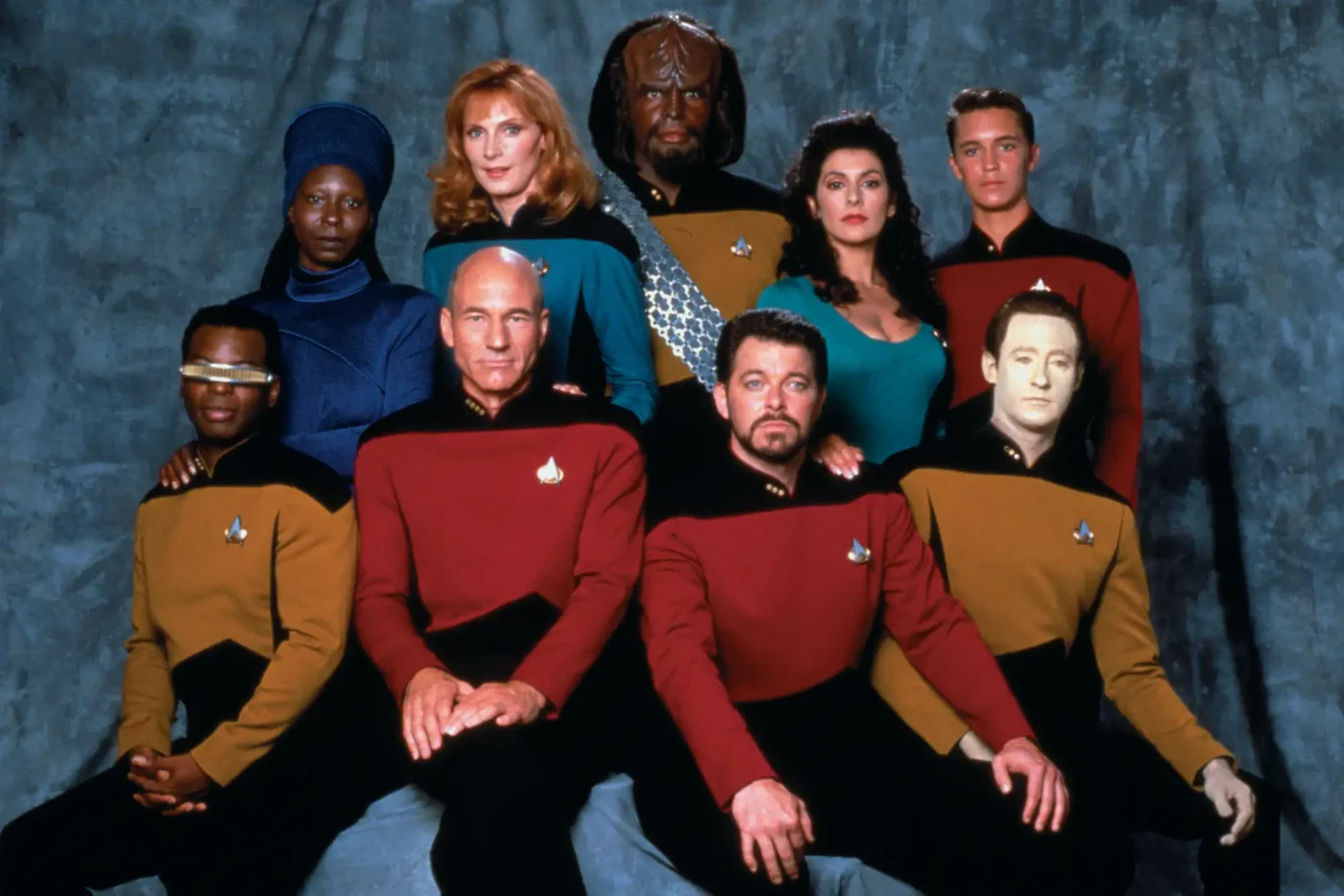 Pictured are from left, front row, American actor LeVar Burton (as Lieutenant Commander Geordi La Forge), British actor Patrick Stewart (as Captain Jean-Luc Picard), and American actors Jonathan Frakes (as Commander William T. Riker) and Brent Spiner (as Lieutenant Commander Data); from left, back row, American actors Whoopi Goldberg (as Guinan), Gates McFadden (as Doctor Beverly Crusher), and Michael Dorn (as Lieutenant Worf), British-American actress Marina Sirtis (as Counselor Deanna Troi), and American actor Wil Wheaton (as Wesley Crusher)