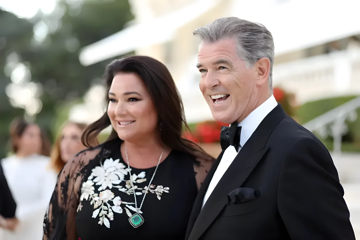 Pierce Brosnan and Keely Shaye Smith smiling at an event, dressed in formal attire.