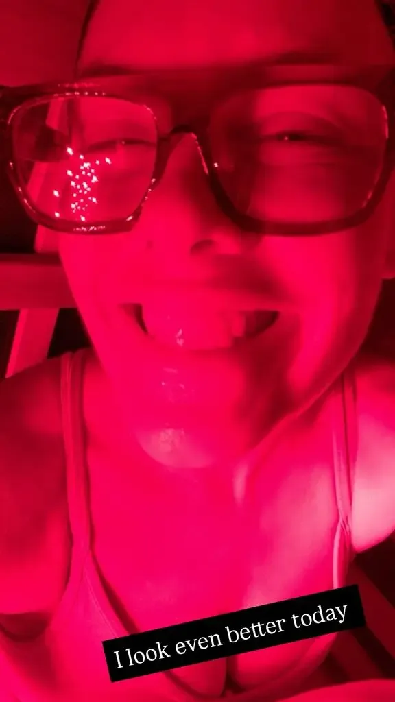 Pink smiling in close-up selfie wearing glasses with red filter
