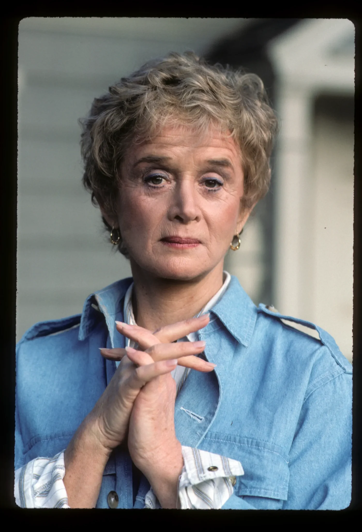 Portrait of actress Barbara Barrie with her hands clasped together, wearing a denim jacket.