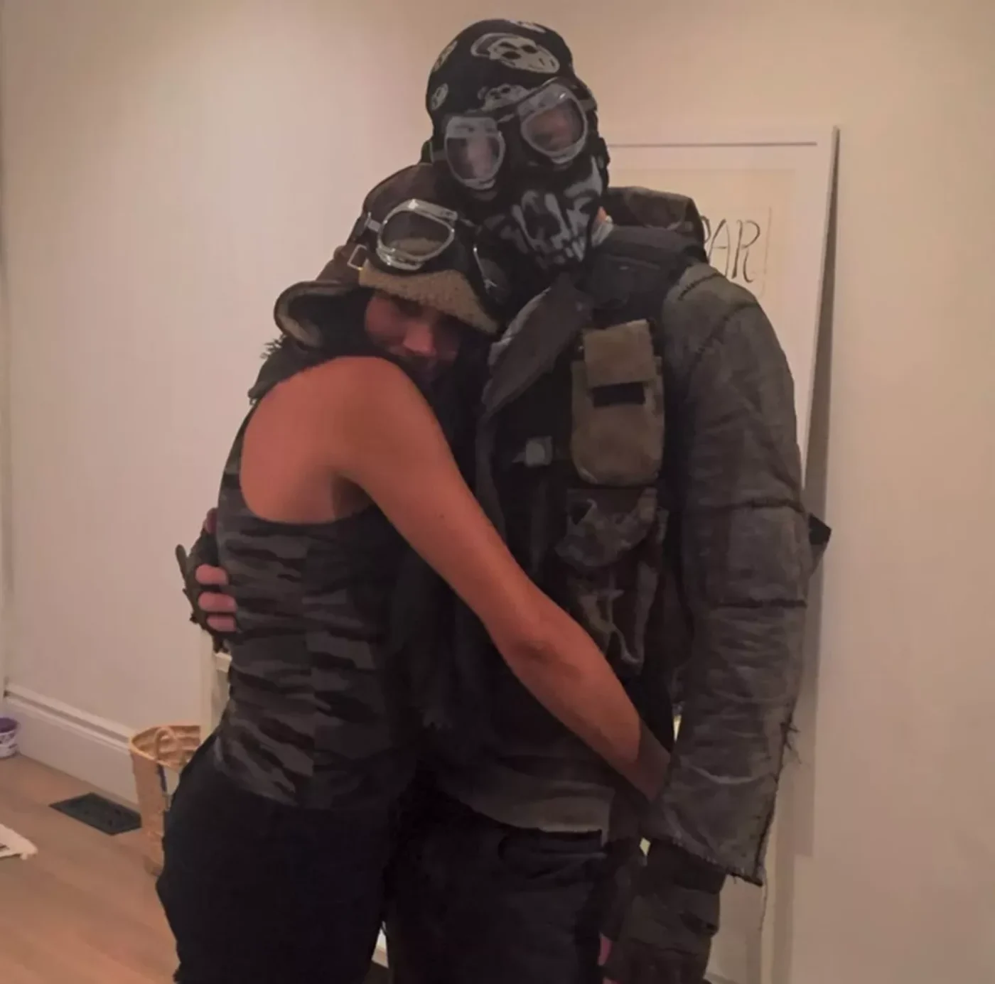 Prince Harry and Meghan Markle dressed in apocalyptic Halloween costumes hugging.