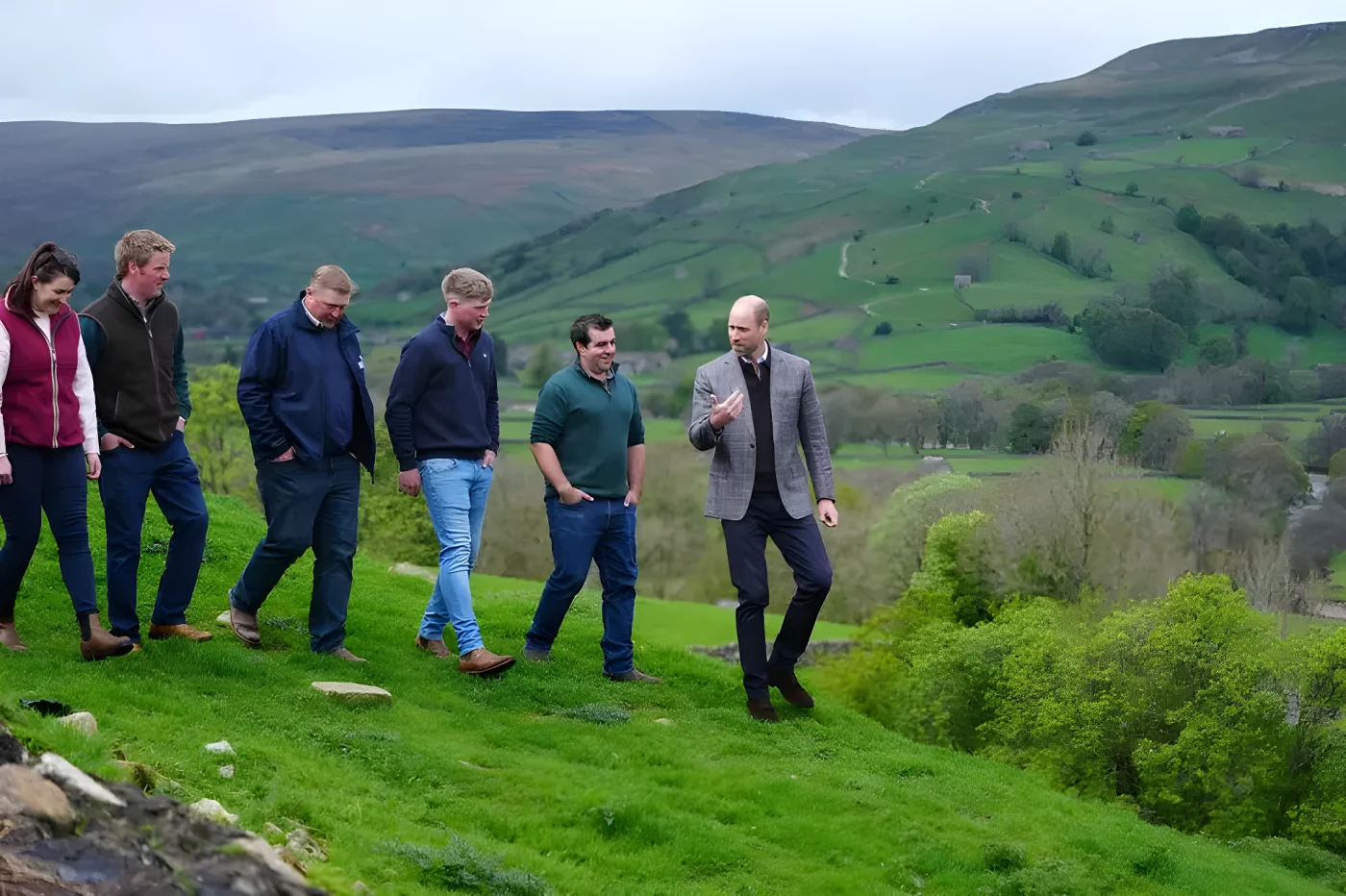 Prince William talks with farmers while walking through hills
