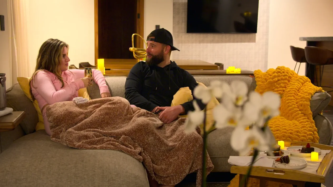 Rachel Aukema and Rob Feeley sitting on a sofa and talking in Love is Blind.