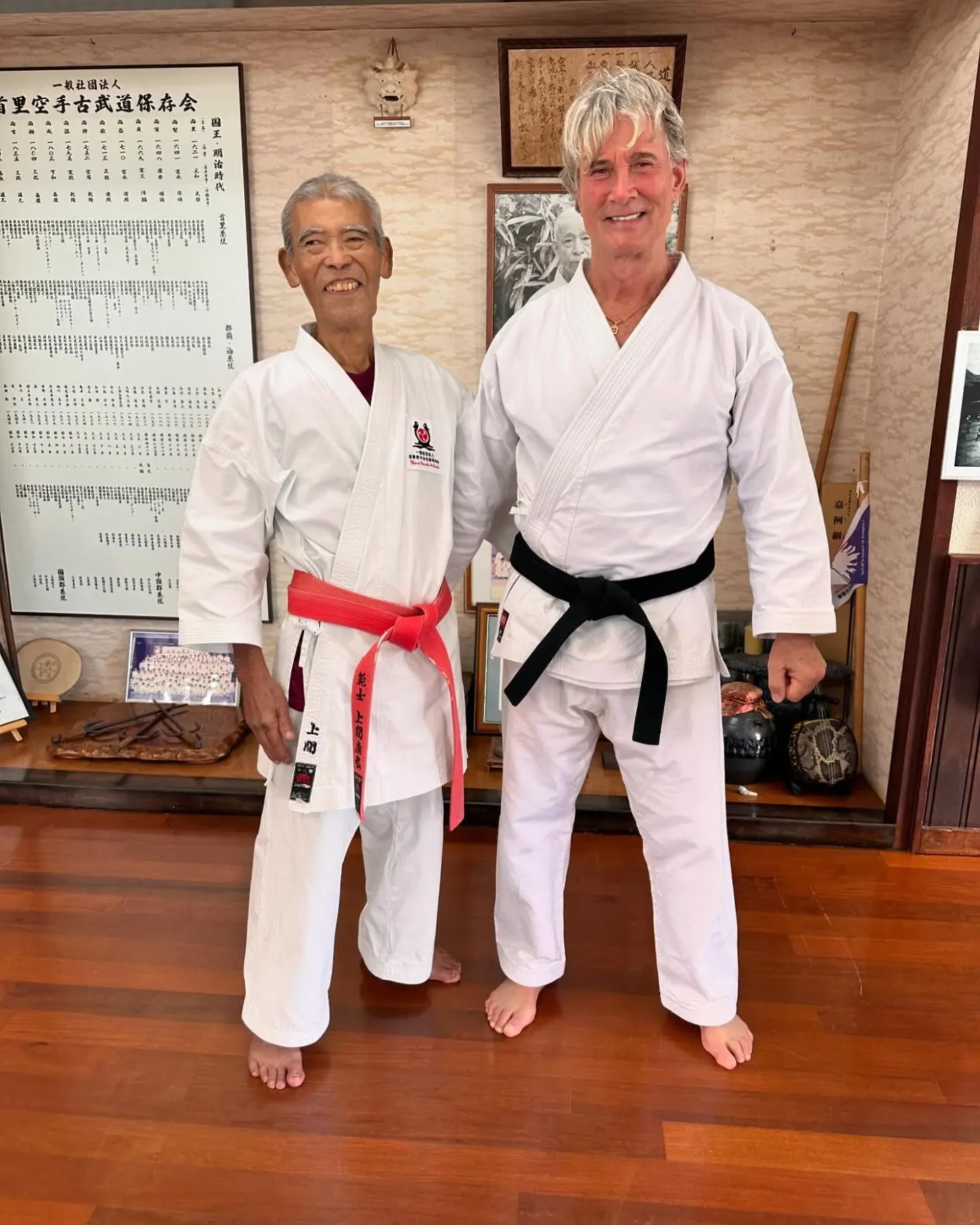 Richard Norton and a martial arts instructor pose together in a dojo, both wearing traditional white gi uniforms.