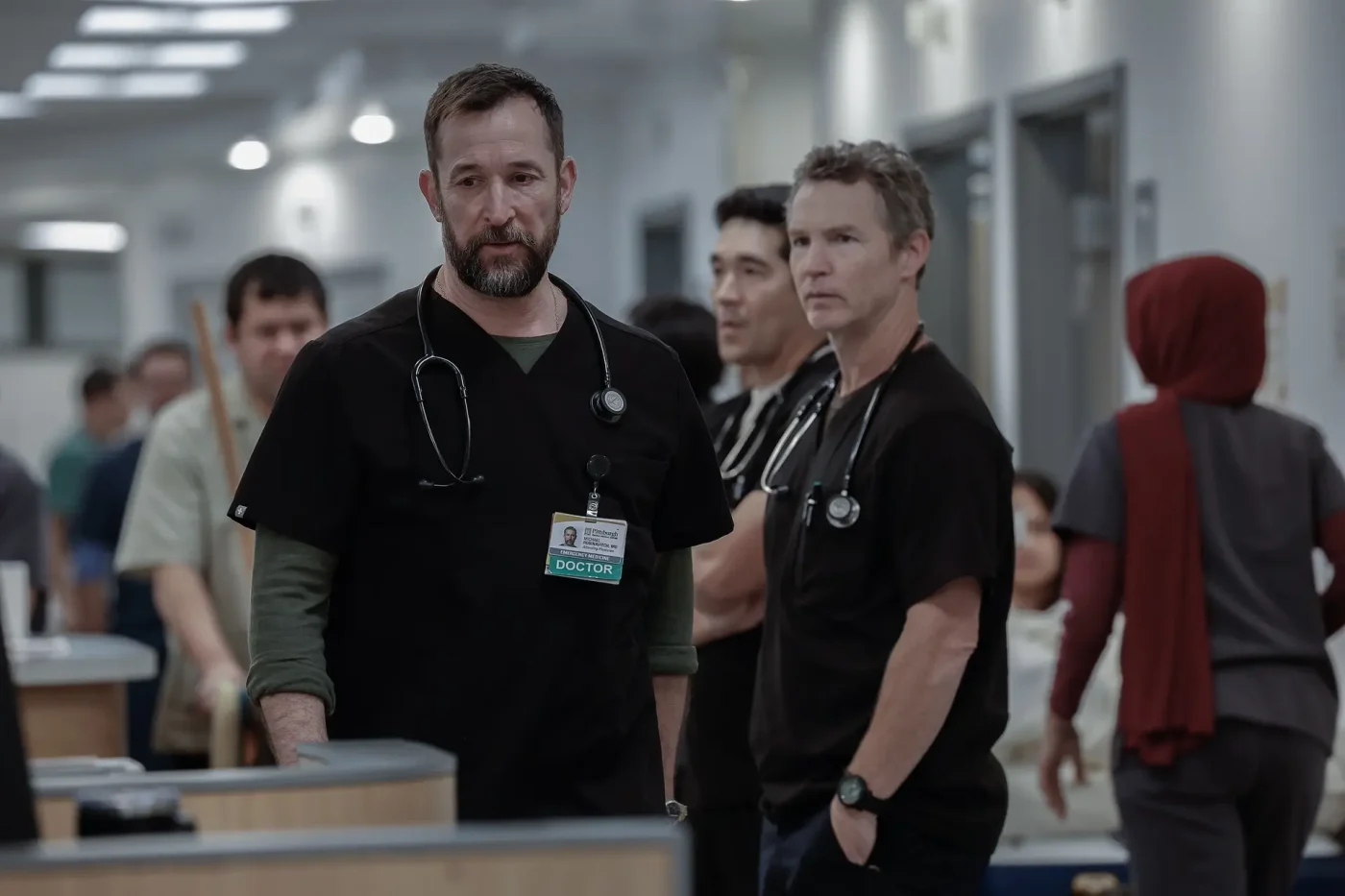 Robby stands in the foreground of a busy hospital hallway, wearing scrubs and a stethoscope, while colleagues stand nearby.