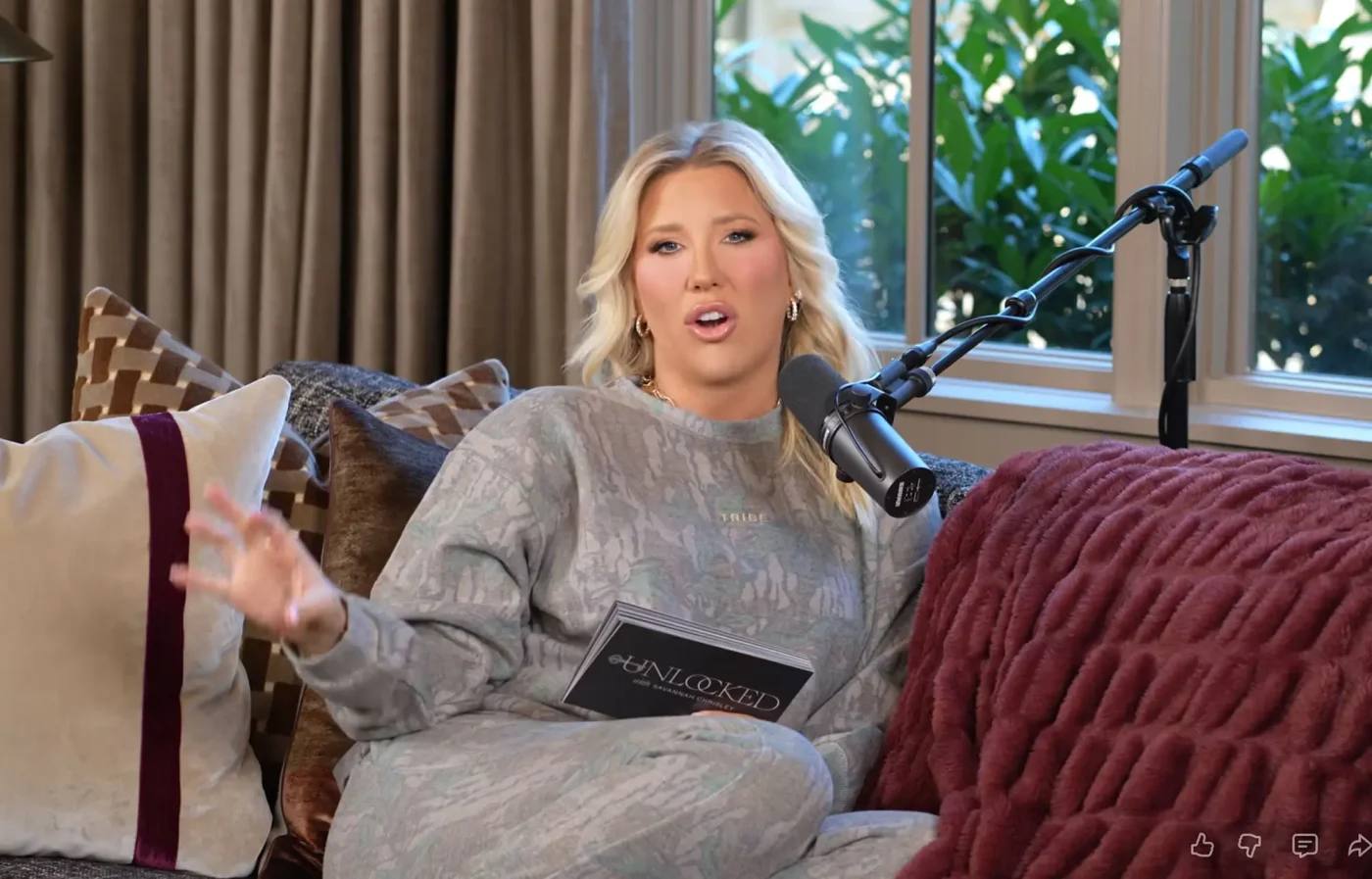 Savannah Chrisley sitting on a couch with a microphone in front of her.