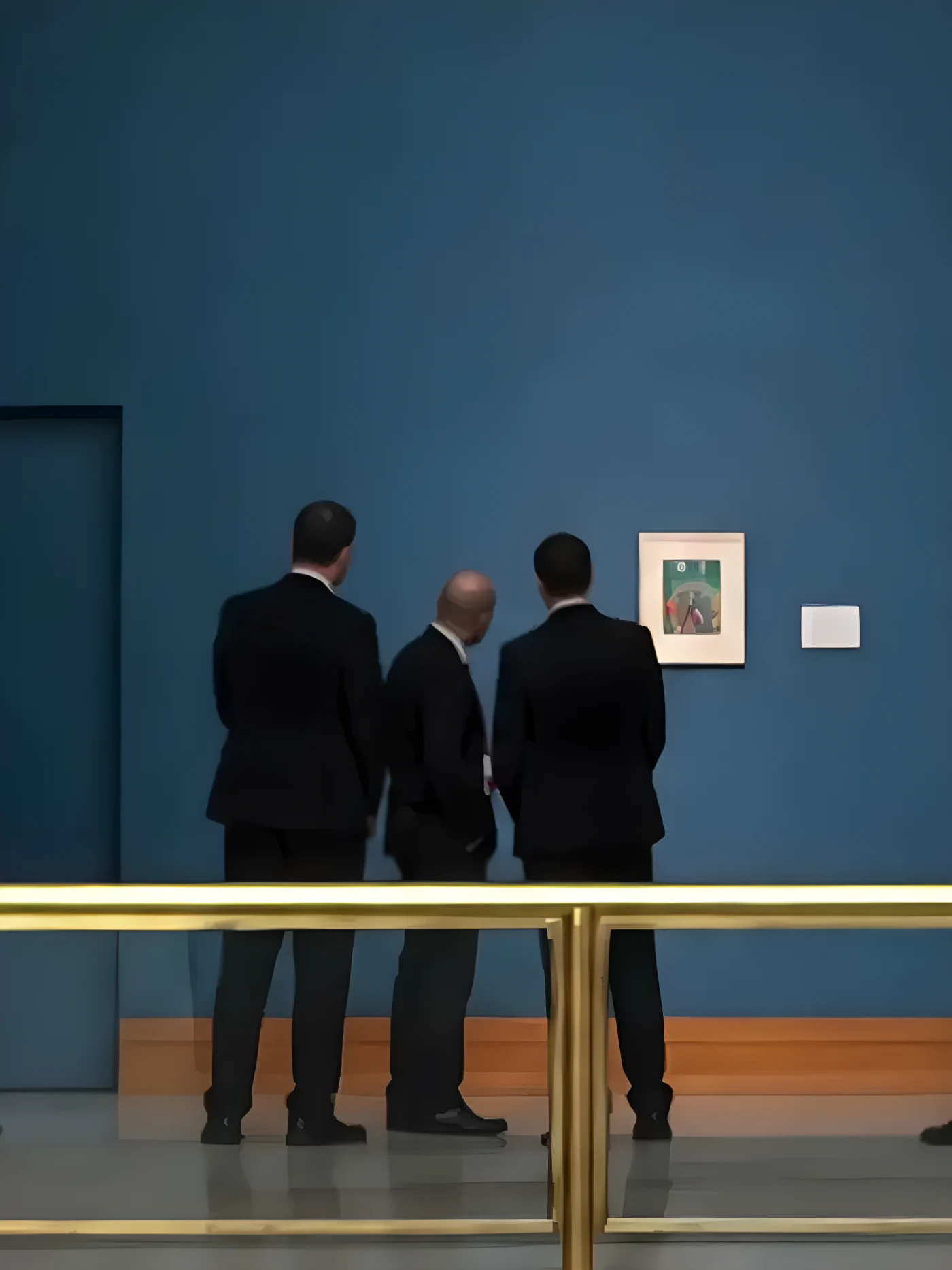 Security personnel view a piece of art hung on a museum wall.