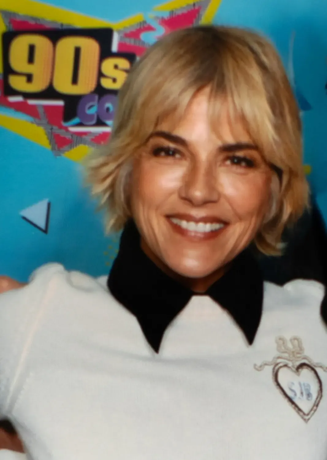 Selma Blair smiling in front of a 90