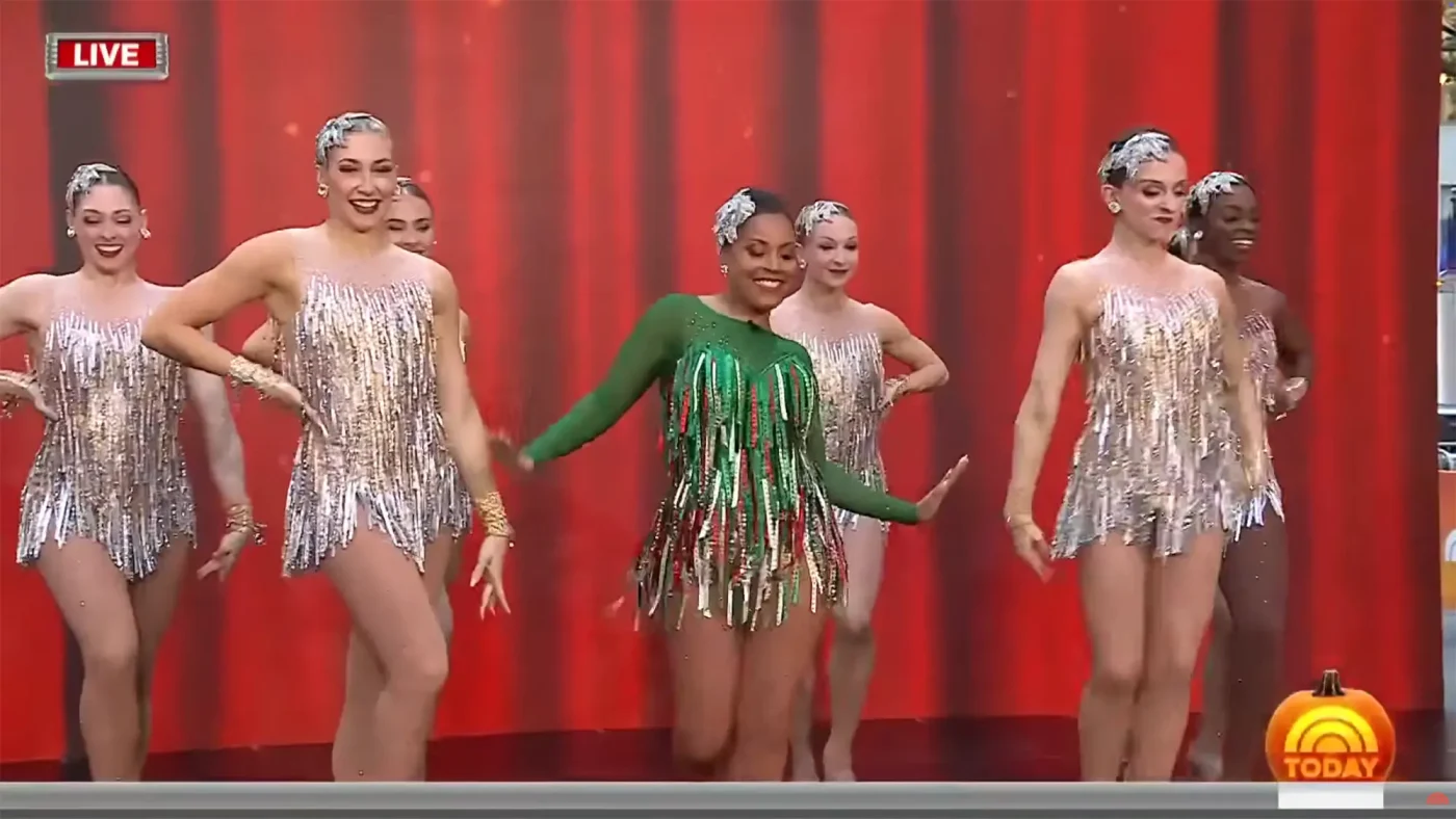 Sheinelle Jones, dressed in a green fringe costume, dances alongside the Rockettes in sparkly silver dresses.