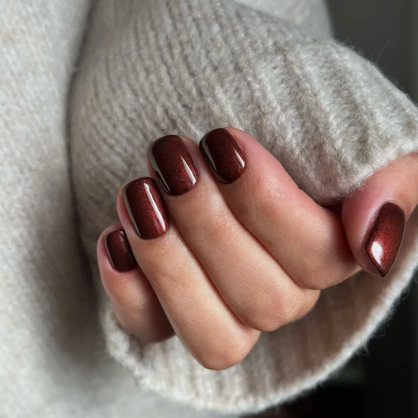 Shimmery brown manicure, gray sweater sleeve visible