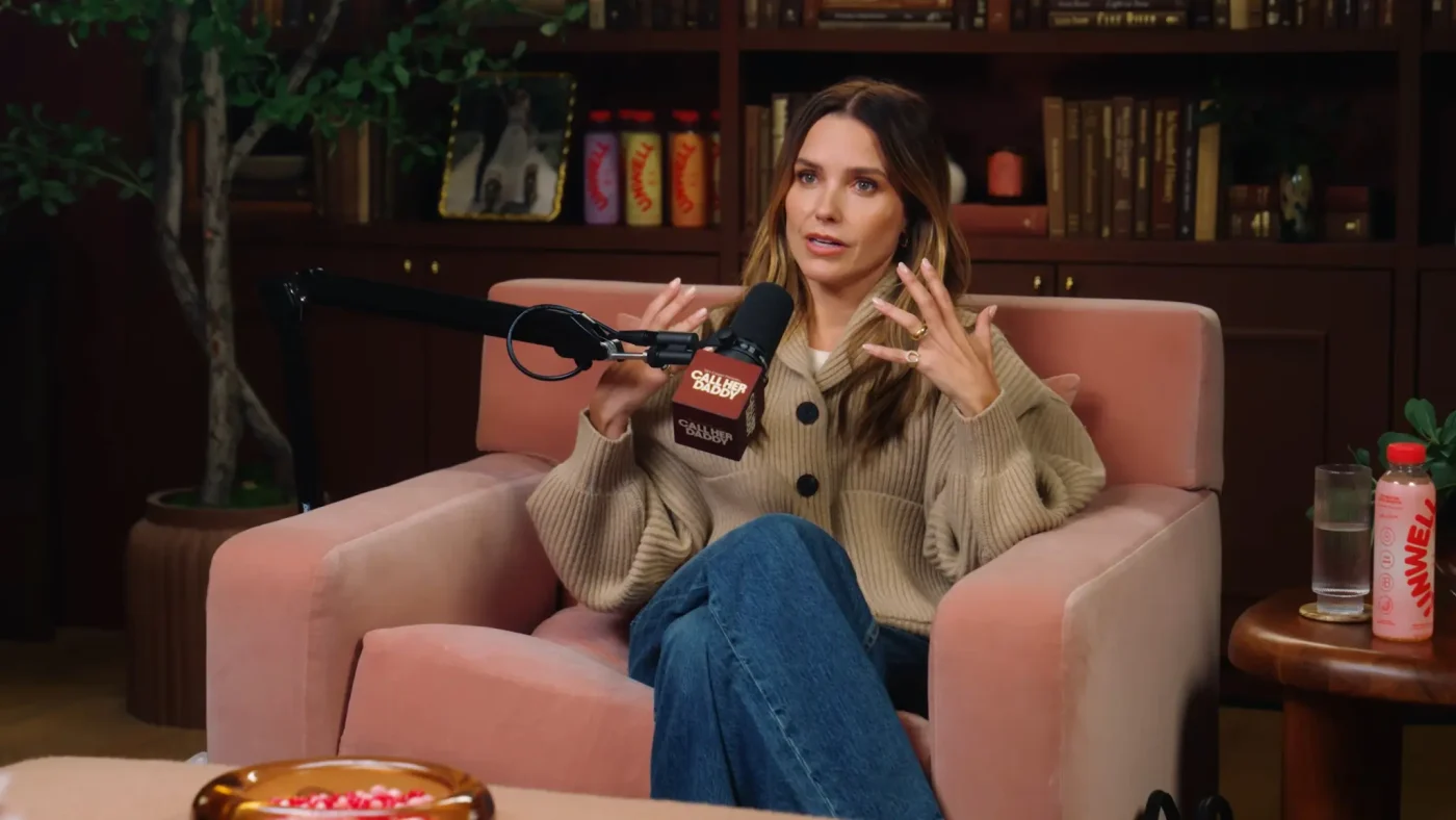 Sophia Bush sits in a pink armchair on the Call Her Daddy podcast, gesturing while speaking into a microphone.