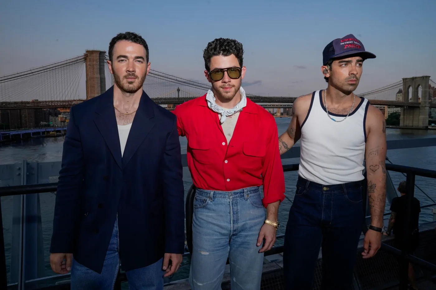 The Jonas Brothers pose backstage with the Brooklyn Bridge in the background.