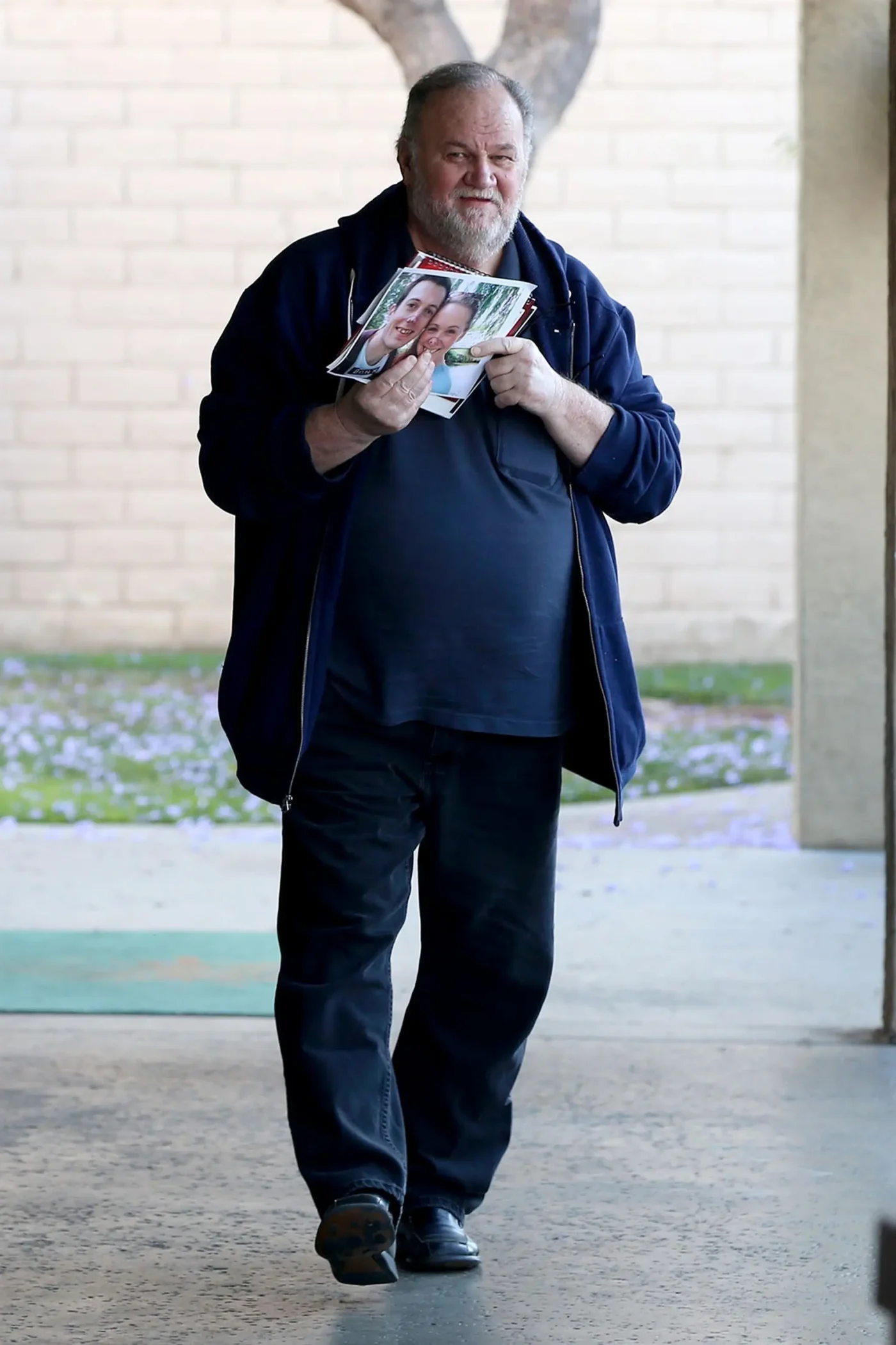 Thomas Markle holding photos while running errands in San Ysidro.