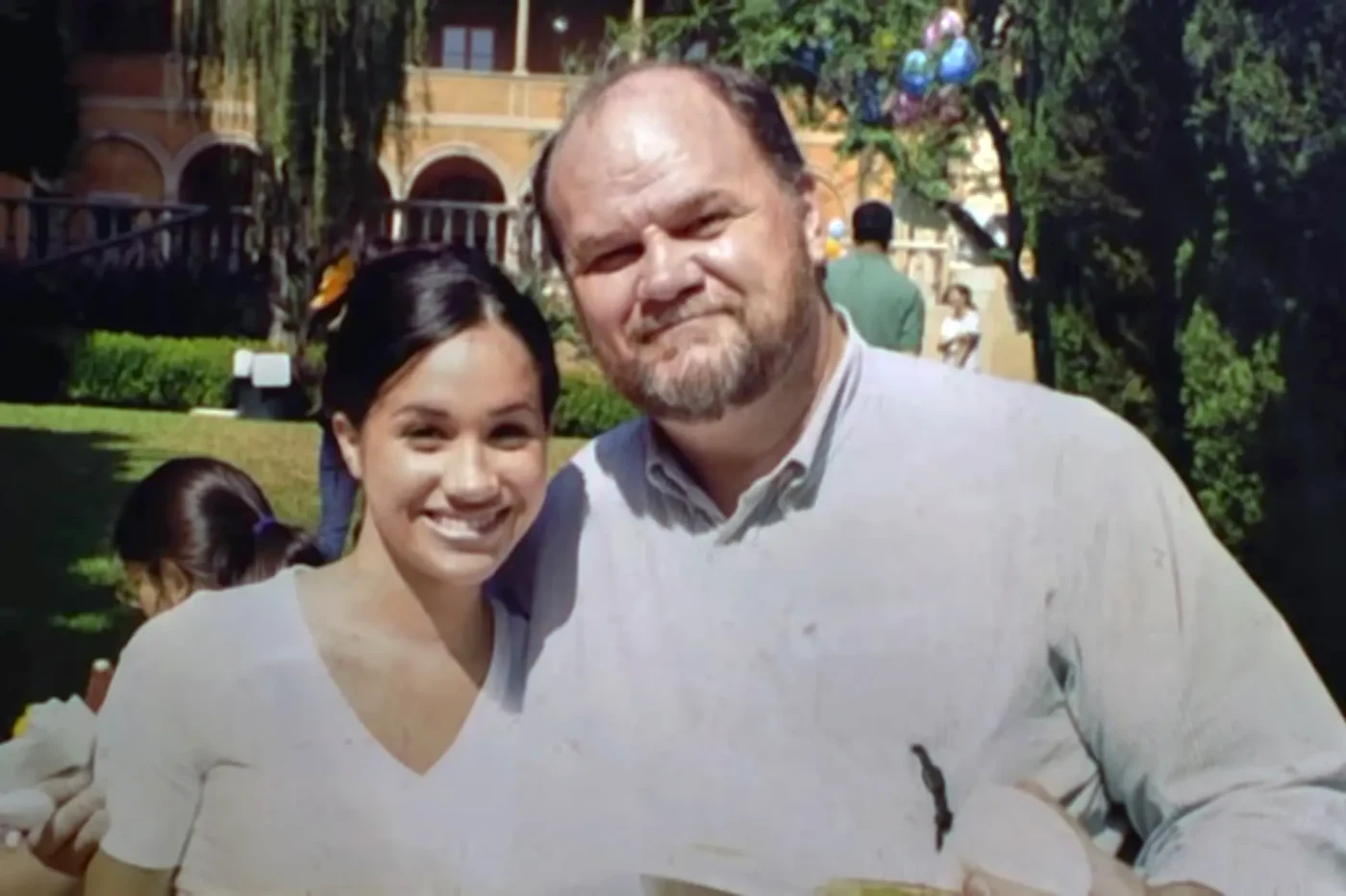 Thomas Markle smiling next to his daughter, Meghan Markle, outdoors.