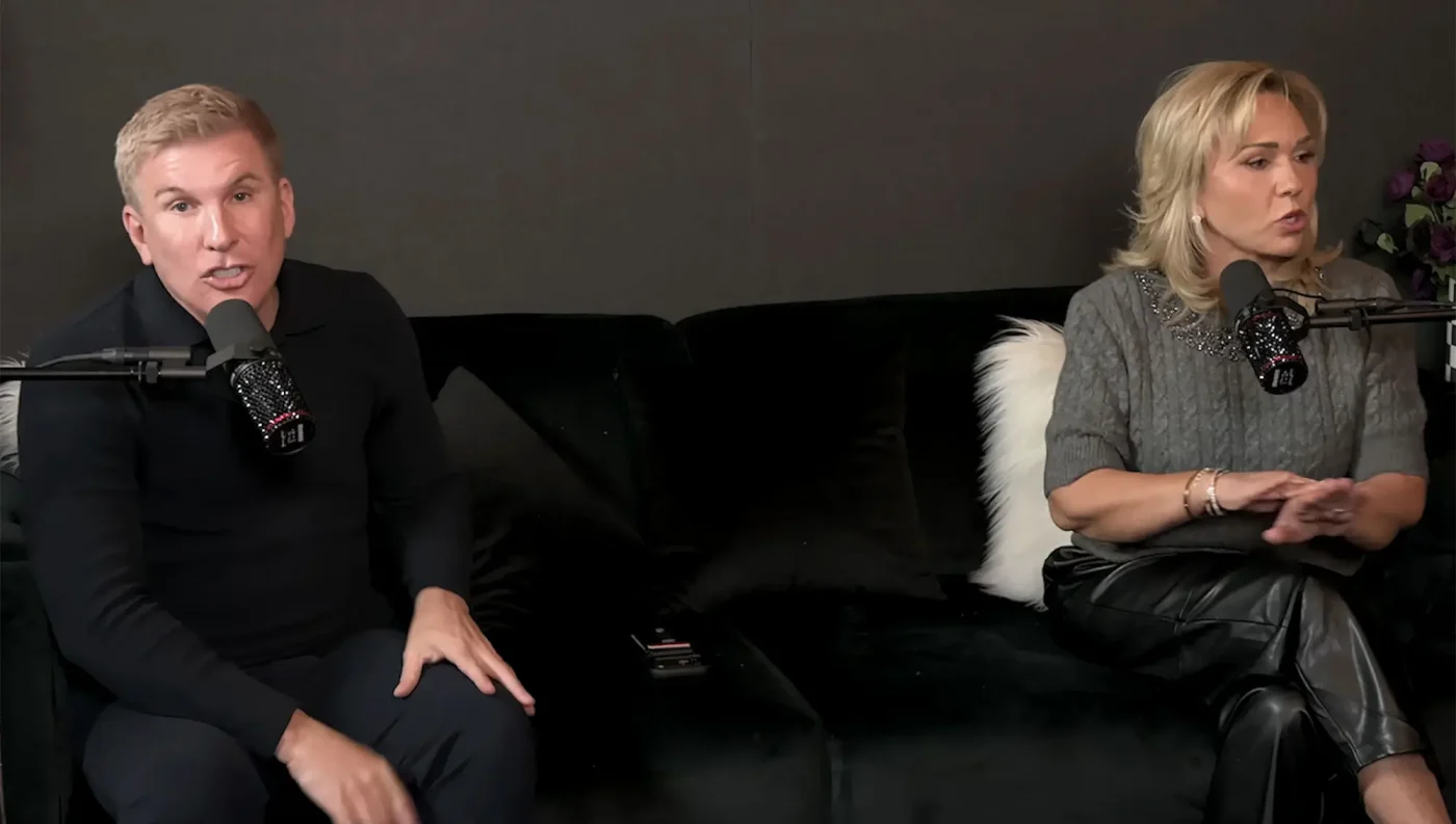 Todd and Julie Chrisley sitting on a couch in front of microphones.