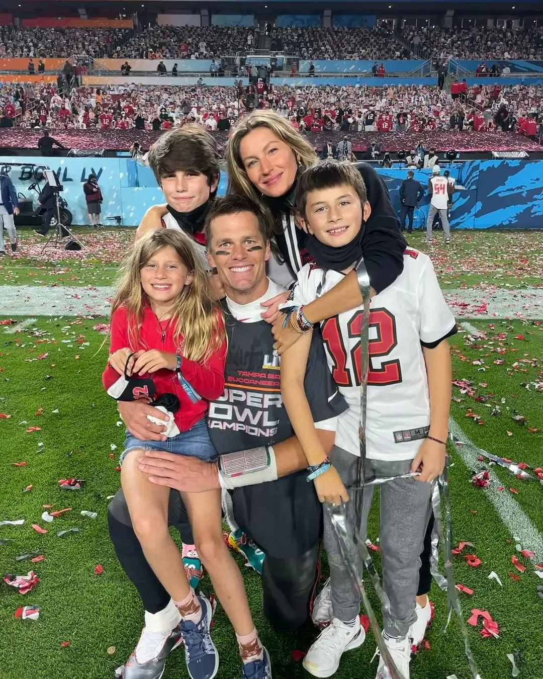 Tom Brady, Gisele Bündchen, and their children pose for a photo on a football field.