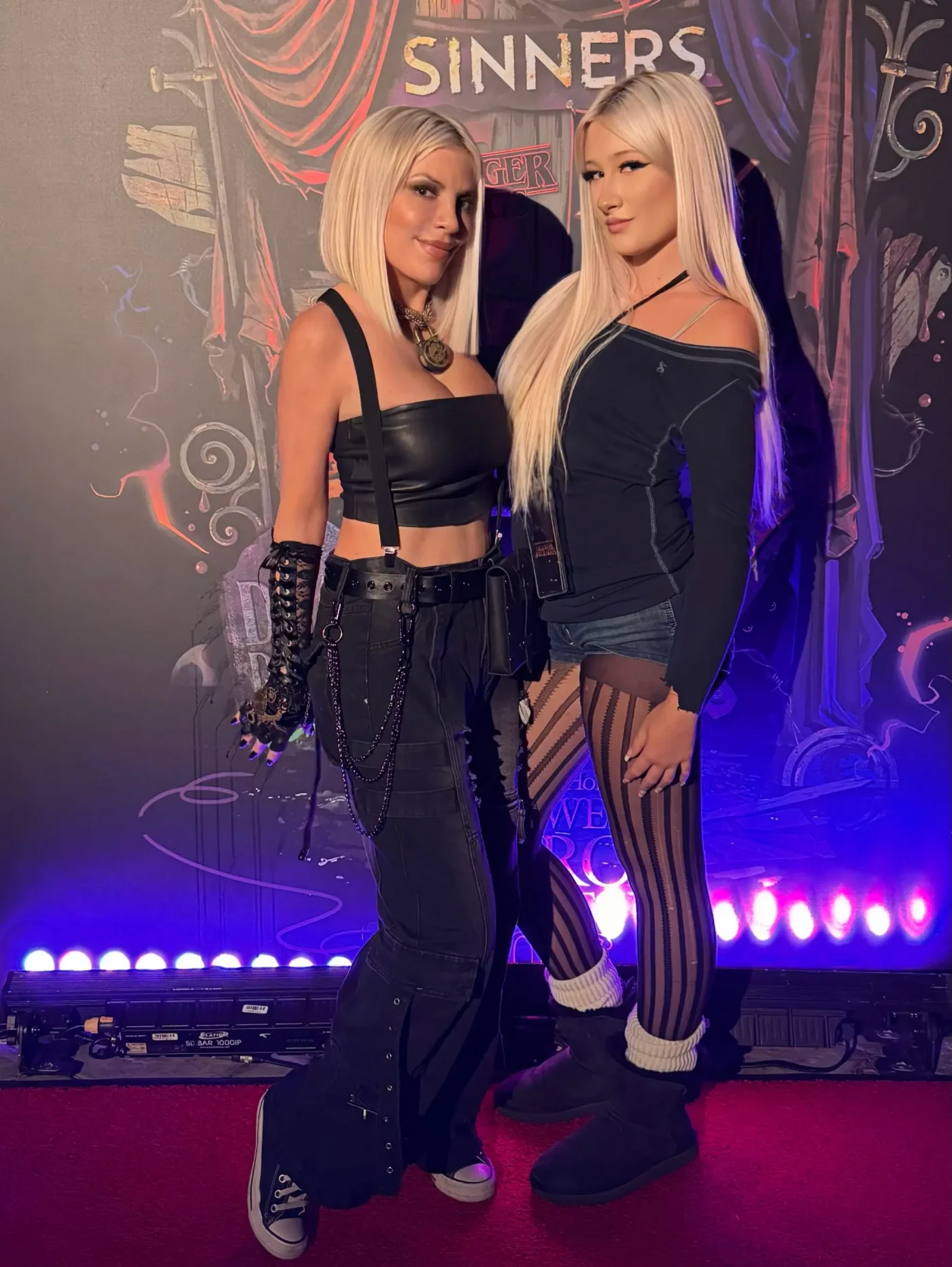 Tori Spelling and her daughter Stella posing together in front of a themed backdrop.