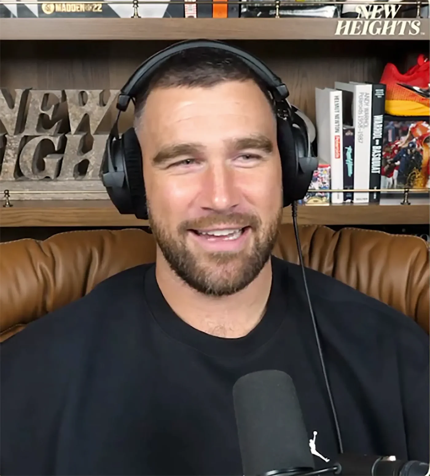 Travis Kelce wearing headphones during a podcast episode.