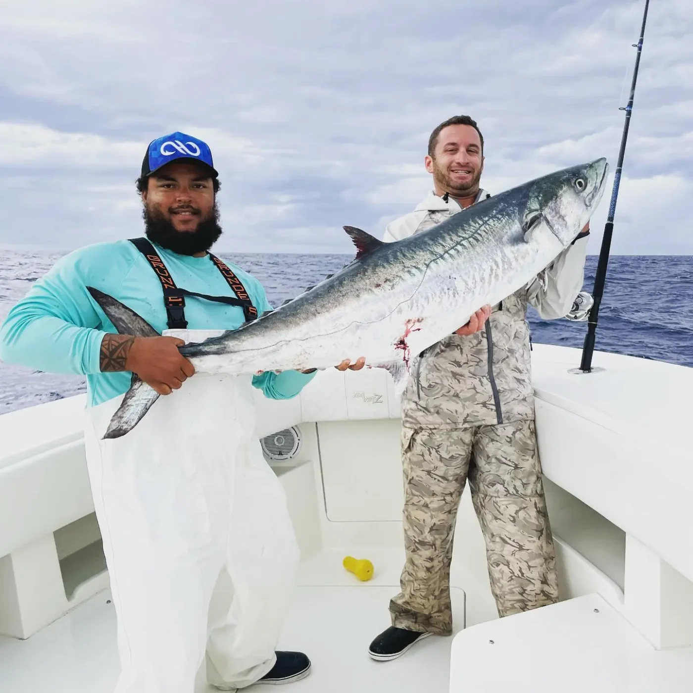 Two men holding a large fish on a boat.