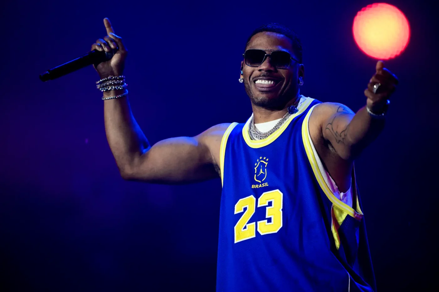 US rapper Nelly performs on stage wearing a blue basketball jersey.