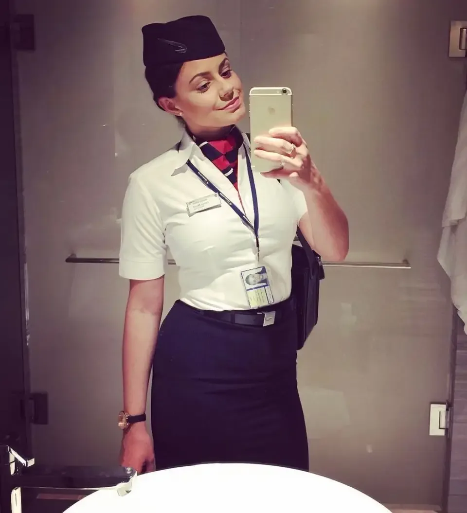 woman taking a selfie in a mirror dressed as a flight attendant